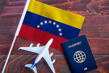 Flag of Venezuela with passport and toy airplane on wooden background. Flight travel concept
