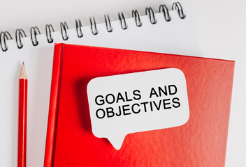 Text Goals and Objectives a white sticker on red notepad with office stationery background. Flat lay on business, finance and development concept