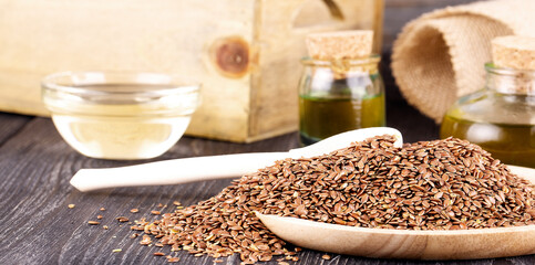 The Sesame oil in glass and seeds on wooden background
