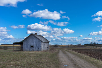 Fototapeta na wymiar An old abandoned small wooden house in the fields sky clouds, barn or scary concept.