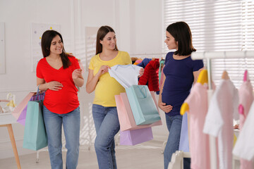 Happy pregnant women with shopping bags in store