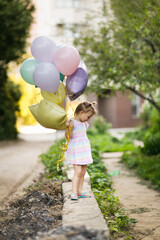 Cute funny little toddler girl with funny ponytails with balloons in pastel colors, tender baby photo with balloons