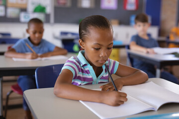 African american girl studying while sitting on her desk in the class at school