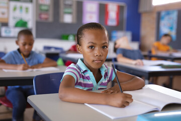 Portrait of african american girl sitting on her desk in the class at school