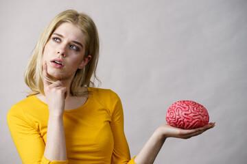 Woman thinking holds brain