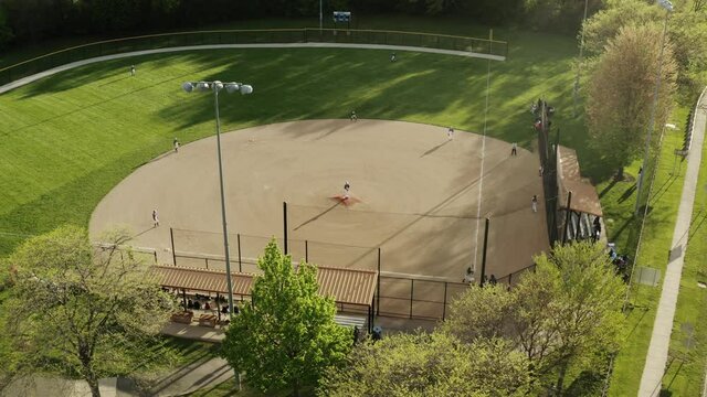 Aerial Drone Shot Of Kids Play Baseball Field At Park On Sunny Day