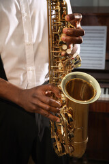 African-American man playing saxophone indoors, closeup. Talented musician