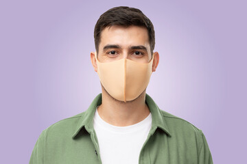 Young man wearing trendy green cargo shirt and beige mask standing isolated on purple background