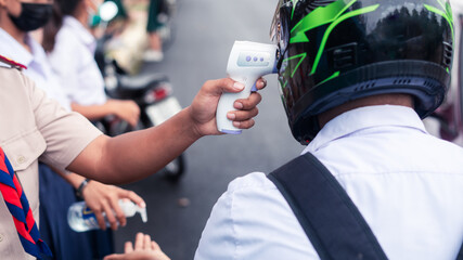 Hand holding Infrared thermometer gun forehead temperature test to check student for protect virus covid-19 symptoms in the school
