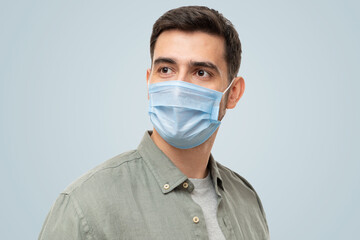 Young man wearing shirt and medical mask standing looking aside