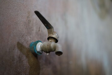 Old faucets on the wall, plastered in the bathroom, have stains and water seepage all the time. The pipe is wrapped with white tape.