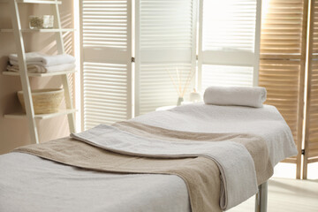 Massage table with soft towels in spa salon