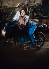 Fototapeta na wymiar Beautiful brunette female mechanic smoking a cigarette while sitting on sportbike in garage