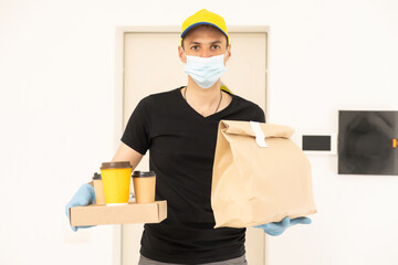 Fototapeta na wymiar delivery man holding package to deliver. Courier hand holding brown box isolated on grey background. Detail of delivery man carrying cardboard parcel with label with copy space.