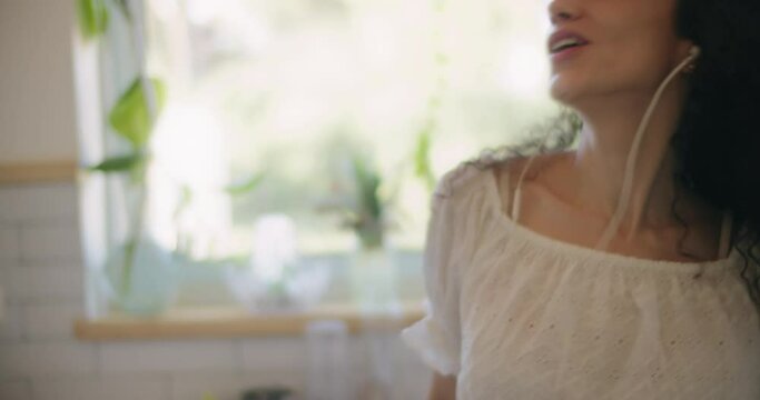 Close up of a happy woman singing and dancing in the kitchen. Slow motion, handheld. 