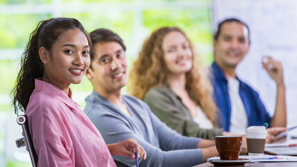 Selective focus face of Caucasian beautiful hipster creative working woman smiling with happiness and confidence while sitting and team meeting together with multiethnic colleagues at cozy company.