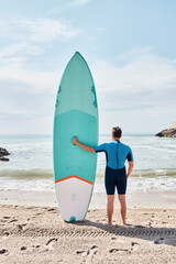 Surfer holding a paddle surf board on the beach