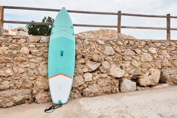 Paddle board leaning against a stone wall on the beach