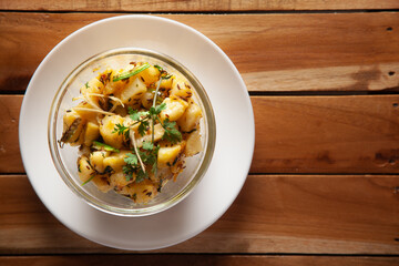 Macro Close-up of Indian vegetarian classic dish Jeera Aloo - Potatoes Flavored with Cumin  garnished with green coriander fresh leaves and green chilli.