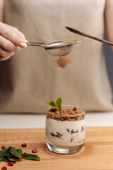 Female hands preparing yogurt with Strawberry for good digestion, functioning of gastrointestinal tract. Summer berries, nuts, fruits, dairy products on table. Healthy food concept.
