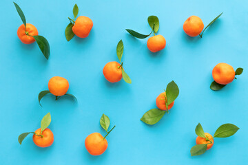 Clementines with leaves on a blue background. Flat lay, top view.