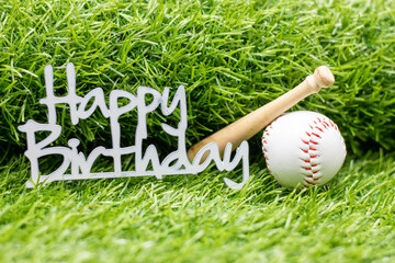 Baseball with Happy Birthday sign are on green grass