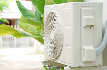 compressor air conditioner(soft focus) hanging on the wall outside the house background beautiful green plants              ......