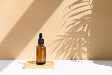 Reusable dark amber glass bottle for oil, cream, lotion or serum on a beige background with a...