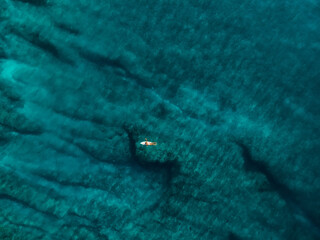 Surfer woman with surfboard in blue ocean. Aerial view with surface of sea