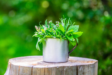 Fresh herbs in a cup on a wooden table.