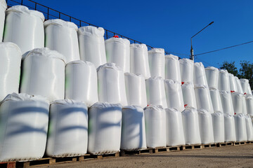 Group of white big bags with chemical fertilizers in a warehouse outdoors.