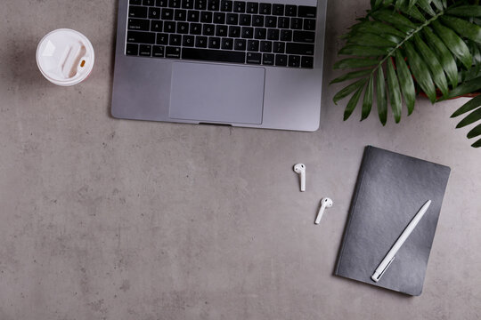 Cropped shot of minimalistic workspace. Tabletop of concrete textured desk with metallic grey laptop. Workplace of a developer concept. Background, copy space for text, flat lay, close up, top view.
