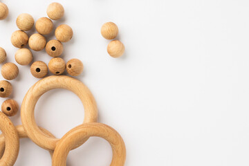 Five wooden rings and beads on white background. Natural wood baby teether. Eco-friendly children toy. Top view, flat lay with copy space.