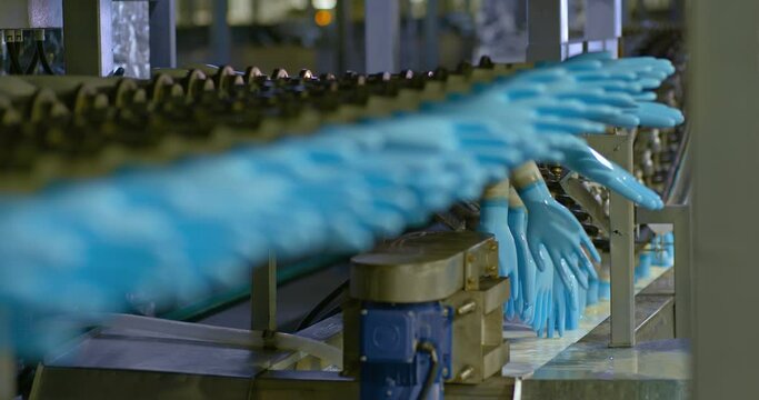 Rubber gloves on a conveyor belt, modern factory equipment. Many blanks of rubber medical gloves are moving along a conveyor belt, a workshop in a factory. 4k, ProRes