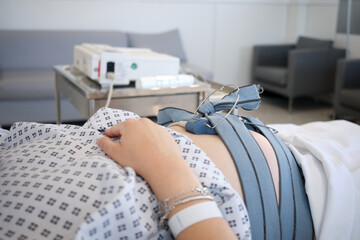 Pregnant woman being monitored by cardiotocography from a monitor. Pregnancy care techology