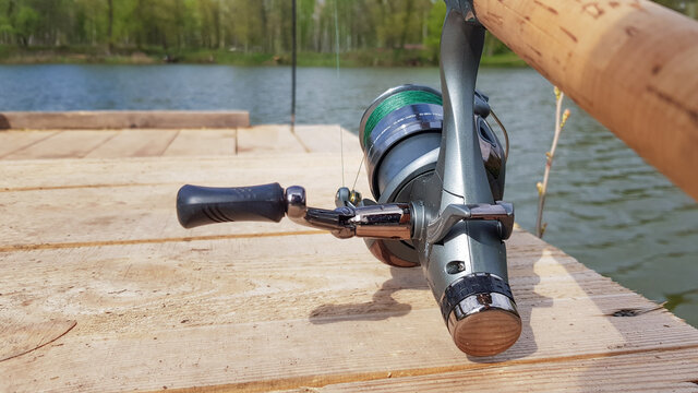 Carp fishing rod isolated on the lake and wooden bridge. Carp feeder spinning reel close up. Fishing for carp on the lake. Fisherman's equipment.