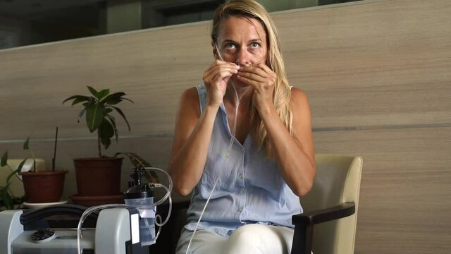 Girl using Oxygen breathing machine at home. Woman put tube of breathing device for asthma and coronavirus in nouse. person have problem with lungs.