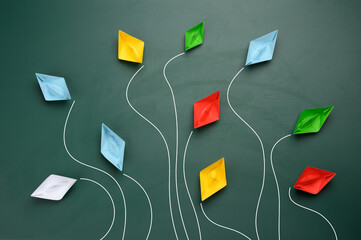 a group of multi-colored paper boats flies in different directions on a green background