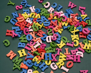 multicolored wooden letters of the english alphabet on a green background