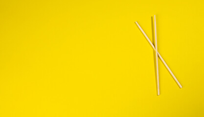 two wooden chopsticks on a yellow background