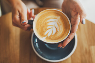 Tasty cappuccino in cup on wooden table