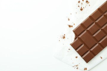 Tasty chocolate bar on paper on white background