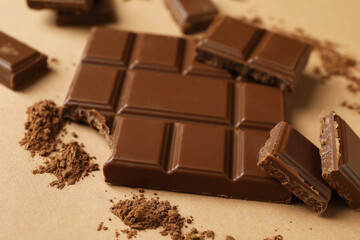 Tasty chocolate bar and powder on beige background