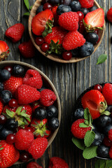 Bowls with berry mix on wooden background