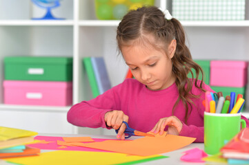 Porait of cute little girl is cutting paper