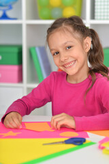 Porait of cute little girl is cutting paper