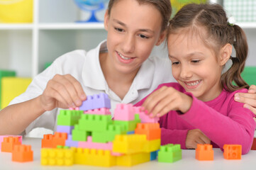 Brother and sister playing with colorful plastic blocks together