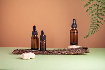 Serum glass bottle set on brown and green background. Composition with natural materials: tree...
