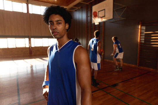 Portrait Of Mixed Race Male Basketball Player With Team In Background