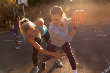 Diverse female basketball team wearing sportswear and practice dribbling ball